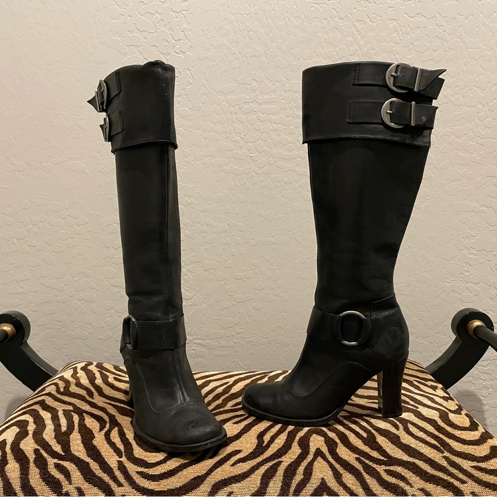 Knee high black boots with buckle details.